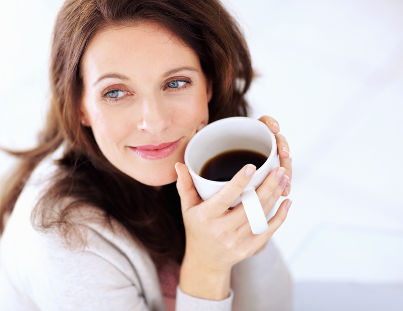 Happy woman having coffee looking away in thought